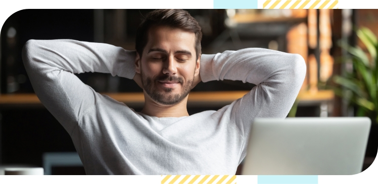 Young man sits in front of his laptop with closed eyes and relaxes
